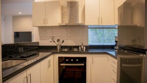 A modern kitchen with white cabinets, a stainless steel range hood, a built-in oven, and a refrigerator. - w Striking 1BR in Miraflores (Lima)