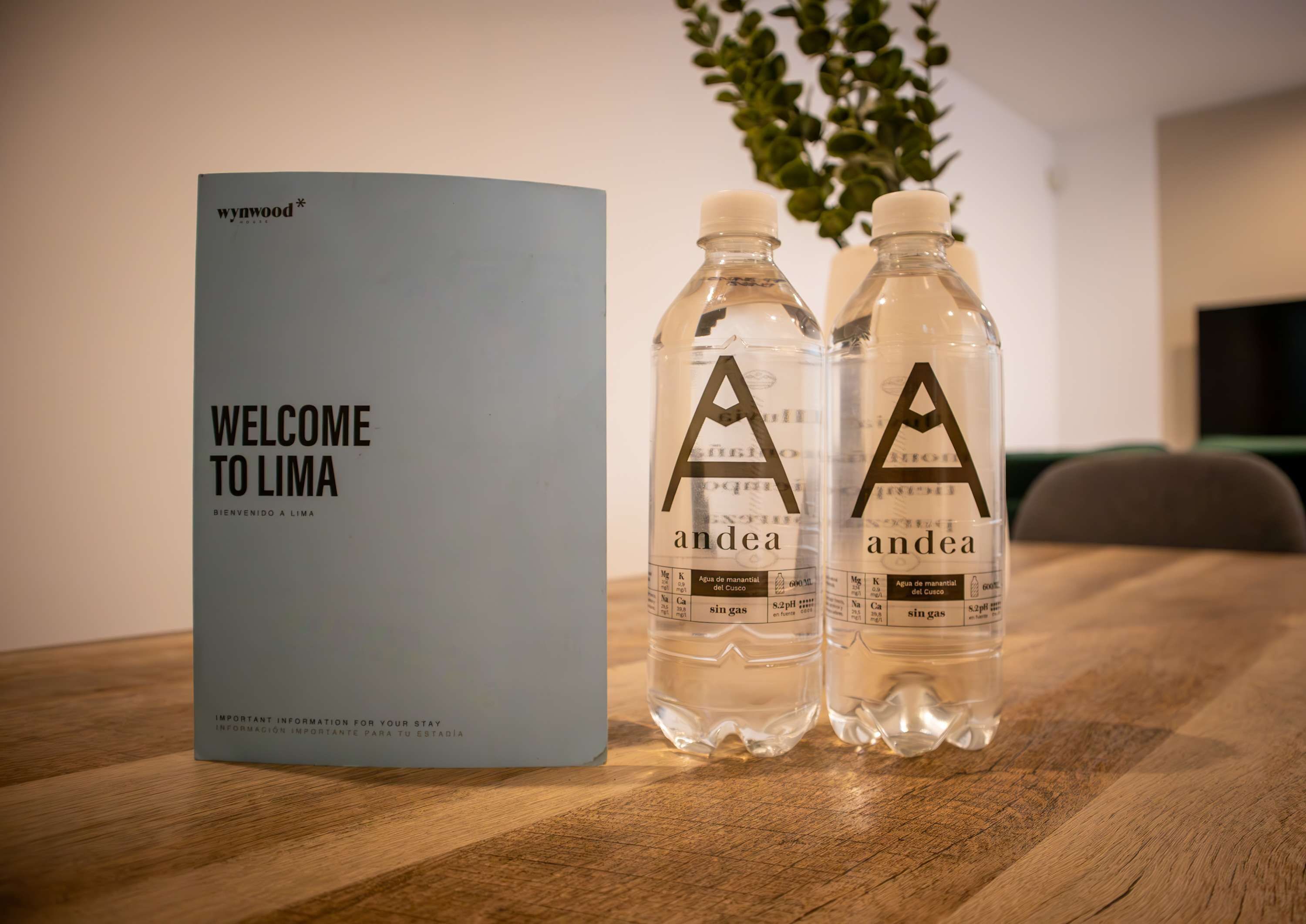 A welcome brochure and two water bottles with labels on a wooden table.