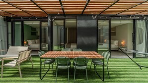 A modern outdoor dining area with a wooden table and chairs, surrounded by a glass wall and a wooden pergola. - w Spacious 3BR w Outdoor Dining Terrace in Laureles (Medellín)