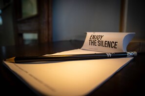 A desk with a notepad, a pen, and a card that reads "ENJOY THE SILENCE."