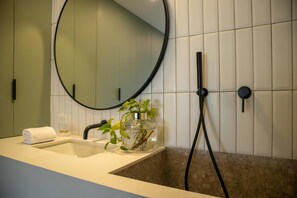 A bathroom with a sink, mirror, and shower.