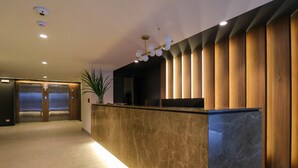 A modern reception area with a marble counter, wooden paneling, and a ceiling light fixture. - w Impressive 2BR With Balcony in Miraflores (Lima)