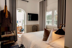 A hotel room with a bed, a TV mounted on the wall, a chair, and a view of the outdoors through a window. - w Suite in Casa Wynwood Miraflores (Lima)