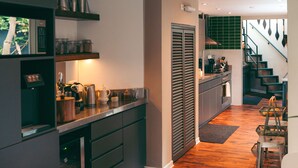 A modern kitchen with dark cabinetry, wooden herringbone flooring, and pendant lighting. - w Suite in Casa Wynwood Miraflores (Lima)