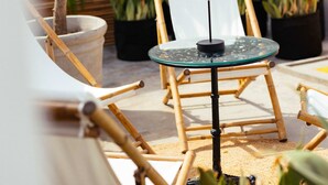 A sunlit outdoor seating area with a glass table, bamboo chairs, and potted plants. - w Suite in Casa Wynwood Miraflores (Lima)