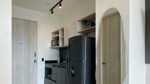 A modern kitchen with a black refrigerator, wooden cabinets, and a marble floor. - w Ocean View 1BR w Near Ciudad Amurallada (Cartagena)