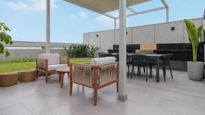 Een overdekt terras met zitgedeelte, een eettafel en een barbecue.