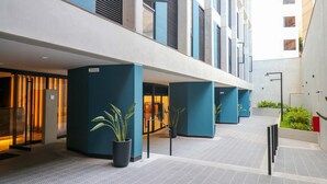 Een moderne hotelgang met een betegelde vloer, blauwe pilaren en potplanten.
