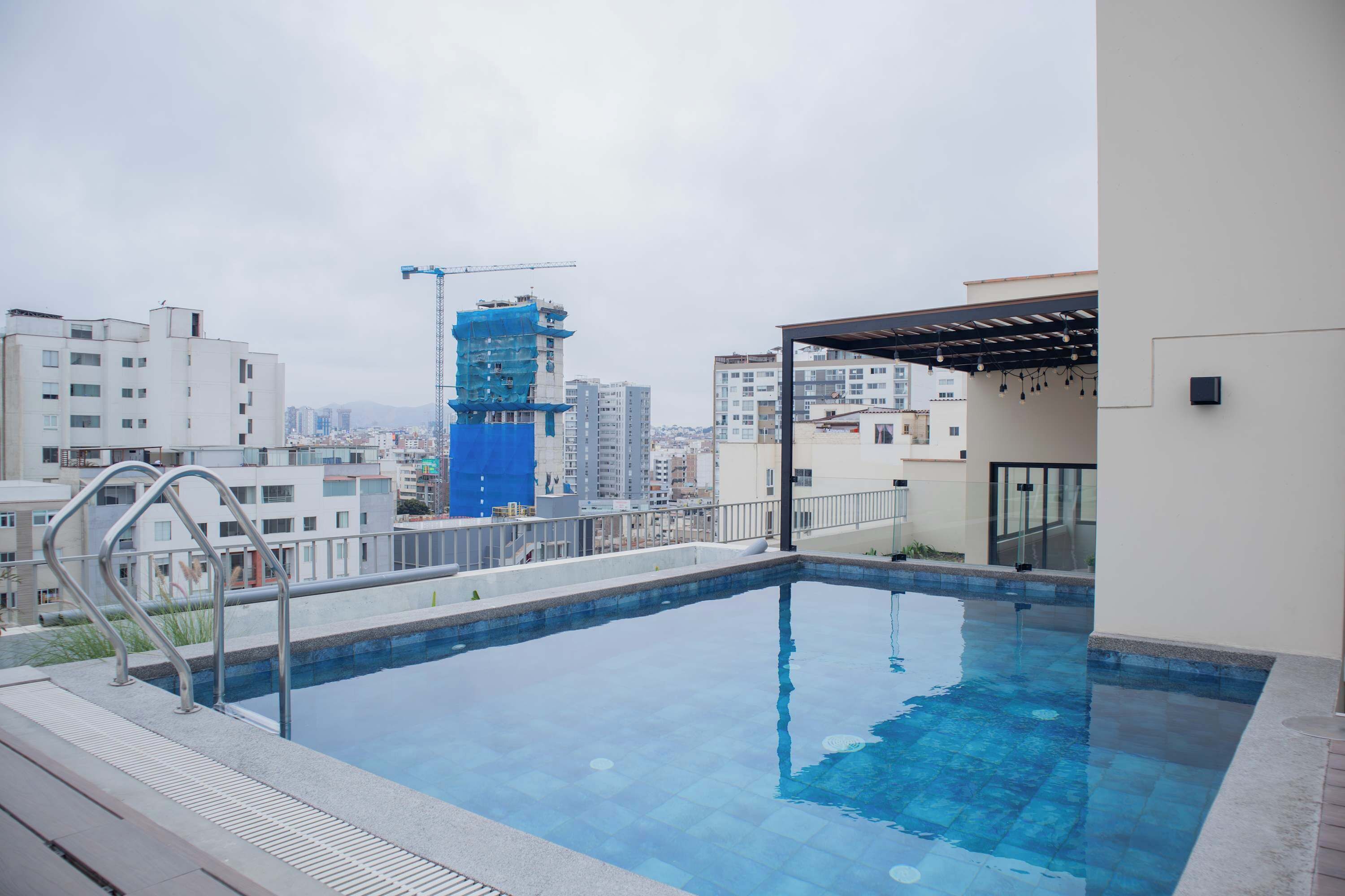A rooftop swimming pool with a view of the cityscape, including a construction crane.
