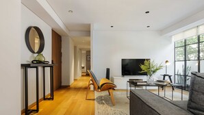 A modern living room with a sofa, a TV, a plant, and a console table with a mirror and vase. - w Amazing 2BR in Roma Norte (Mexico City)