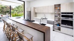A modern kitchen with a central island, bar stools, stainless steel appliances, and a view of the outdoors. - w Mind-blowing 4BR Villa w Pool at Mesa de Yeguas (Anapoima)