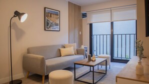 A modern living room with a sofa, ottoman, coffee table, floor lamp, and a painting on the wall. - w Stunning 1BR w Terrace in Miraflores (Lima)