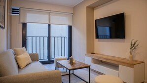 A modern living room with a sofa, a coffee table, and a TV mounted on the wall. - w Stunning 1BR w Terrace in Miraflores (Lima)