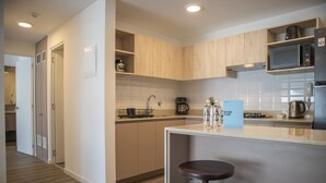 A modern kitchen with wooden cabinets, a built-in microwave, and a coffee maker. There is a bar stool and a welcome sign. - w Fantastic 2BR w Modern Deco in San Isidro (Lima)