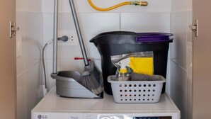 A laundry room with a front-loading LG ThinQ washer and dryer, a hose for water, a mop, and a laundry basket. - w Fantastic 2BR w Modern Deco in San Isidro (Lima)