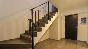 A staircase with wooden steps and black railings, leading to a door with a small window and a phone. - w Stunpedous 2BR w Perfect Balcony in Cusco (Cusco)
