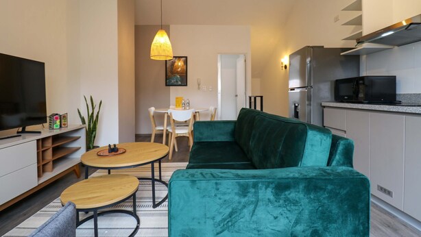 A modern living room with a green sofa, wooden coffee table, and a TV. There is a dining area with a white table and chairs. - w Stunpedous 2BR w Perfect Balcony in Cusco (Cusco)
