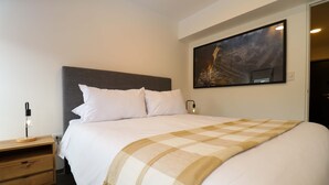 A neatly made bed with a checkered throw blanket, a bedside table with a lamp, and a painting on the wall. - w Stunpedous 2BR w Perfect Balcony in Cusco (Cusco)