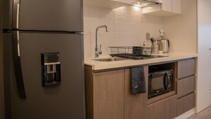 A modern kitchen with a stainless steel refrigerator, a built-in oven, a microwave, and a sink with a dish rack. - w Spectacular 1BR w Terrace in Miraflores (Lima)