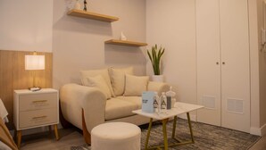 A modern hotel room with a sofa, a small table with amenities, a nightstand, a lamp, a potted plant, and a wardrobe. - w Spectacular 1BR w Terrace in Miraflores (Lima)