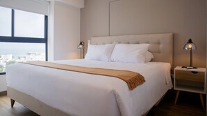 Ett modernt hotellrum med en stor säng, ett nattduksbord och utsikt över staden.