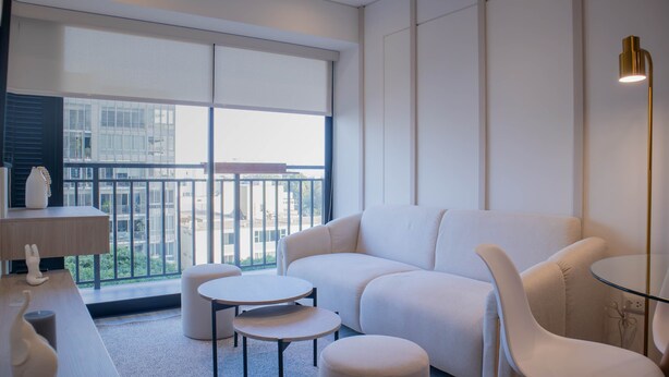 A modern hotel room with a large window, a white sofa, two round tables, and a small white chair. - w Amazing 2BR w Balcony in San Isidro (Lima)