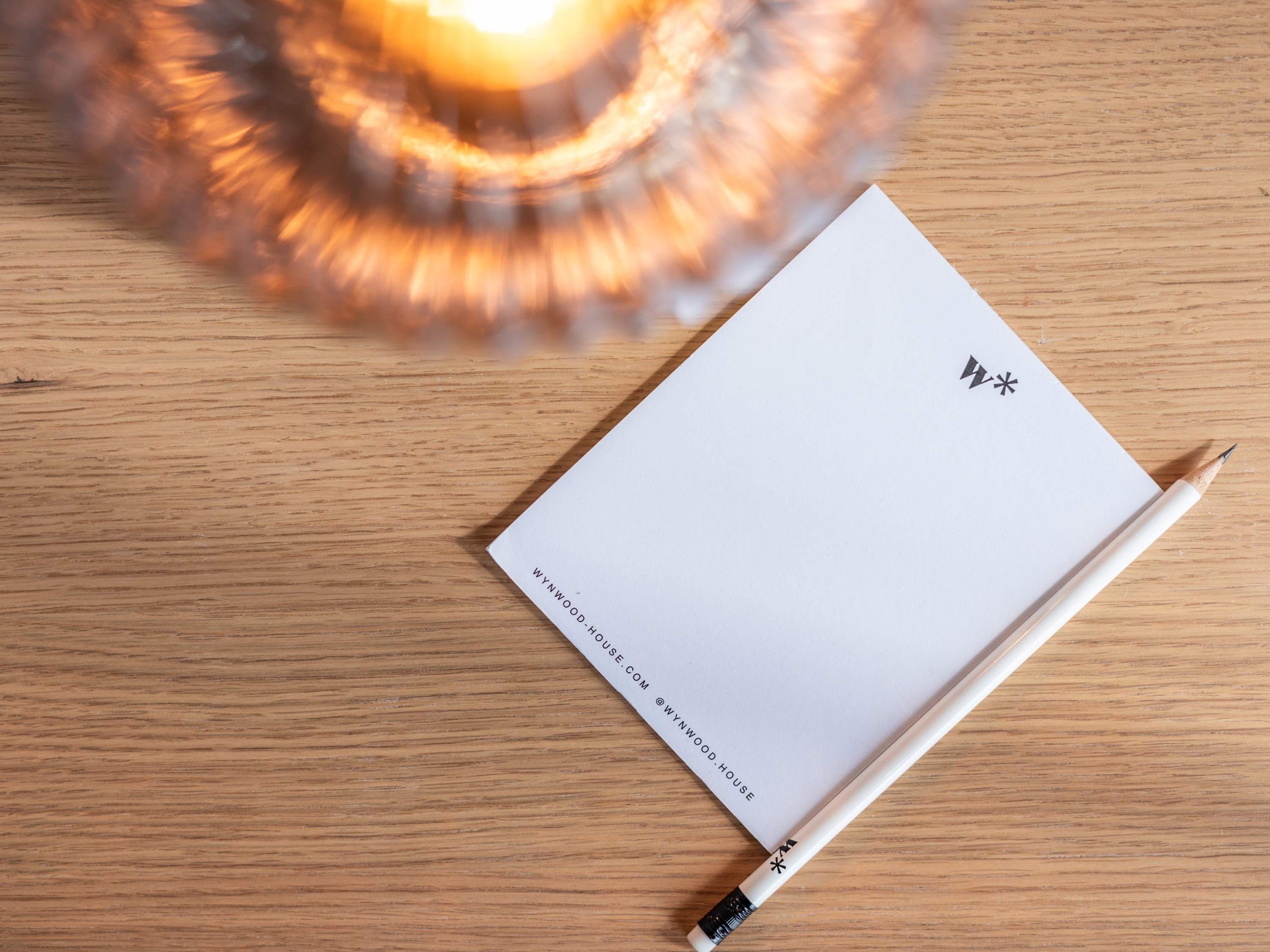 A blank notepad with a pencil on a wooden surface.