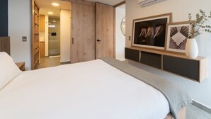 Un dormitorio moderno con una cama grande, armario empotrado y televisor montado.