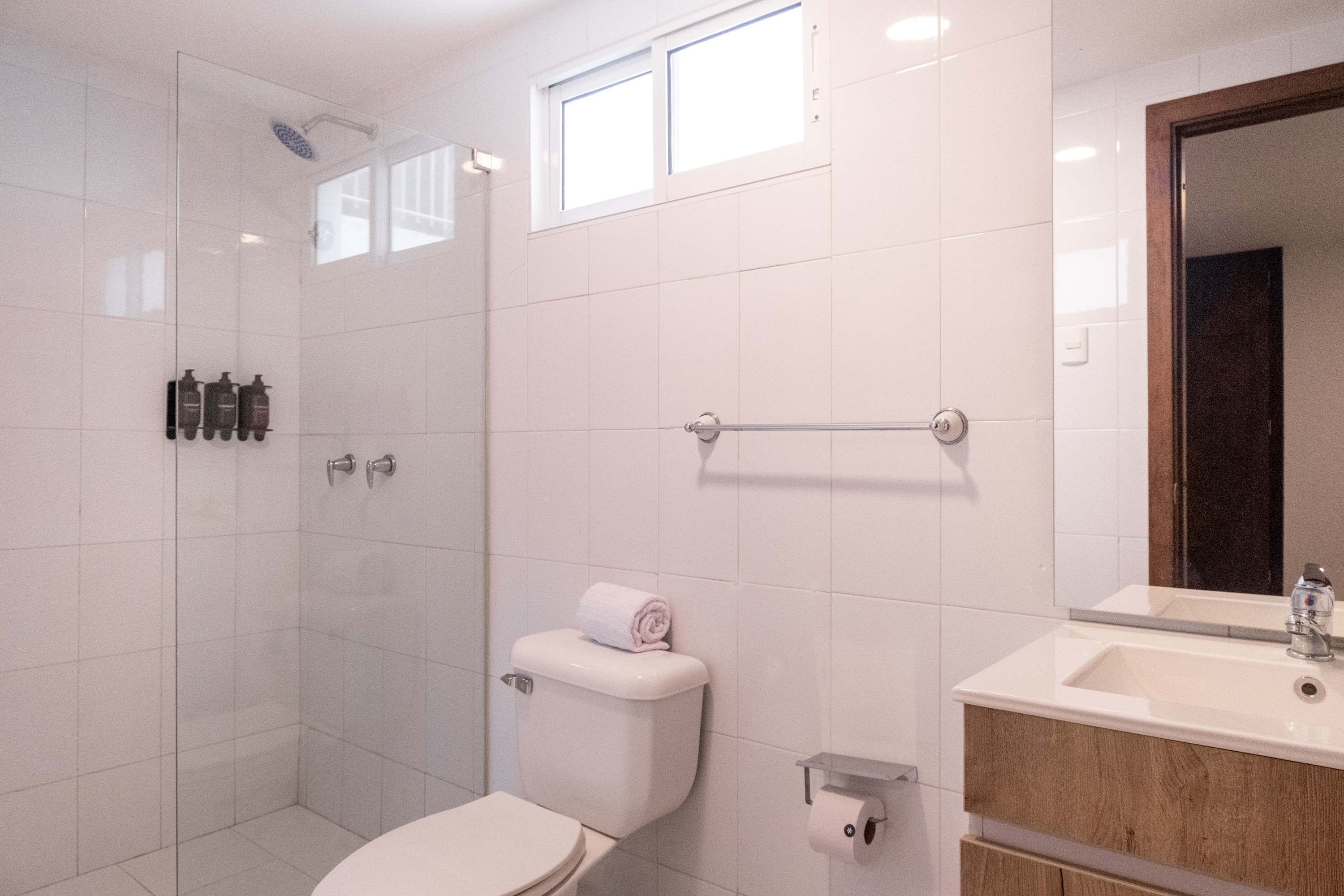Ein modernes Badezimmer mit einer Duschkabine, einer Toilette und einem Waschbecken mit Spiegel darüber.