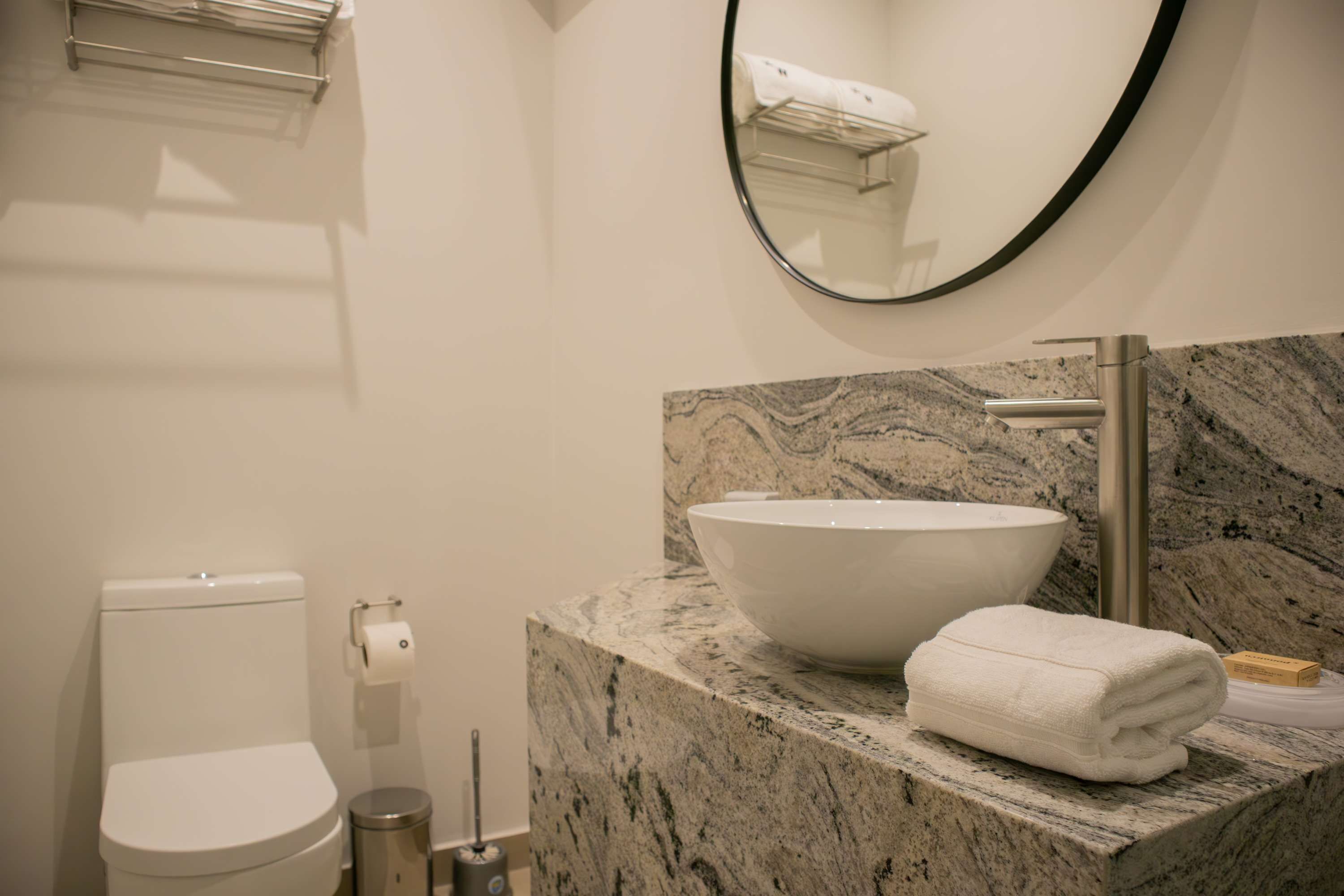 Een badkamer met een marmeren wastafel, toilet, spiegel en handdoek.