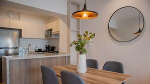 Une cuisine moderne dotée d’un îlot central, d’une table à manger avec des chaises et d’un luminaire suspendu.