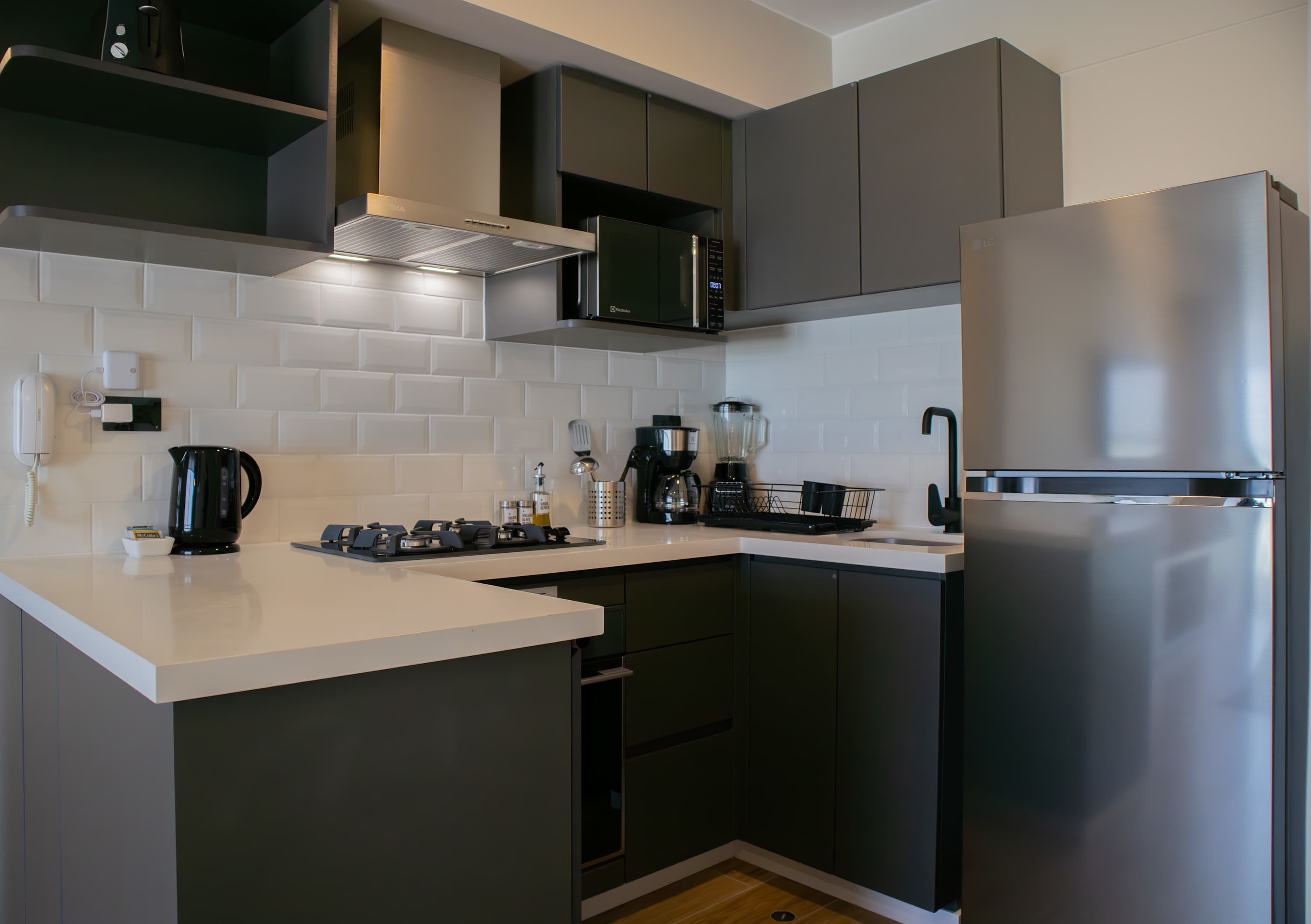 Eine moderne Küche mit einem Edelstahlkühlschrank, einer Mikrowelle und einer Kaffeemaschine.