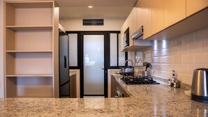 A modern kitchen with granite countertops, stainless steel appliances, and a view into the dining area.