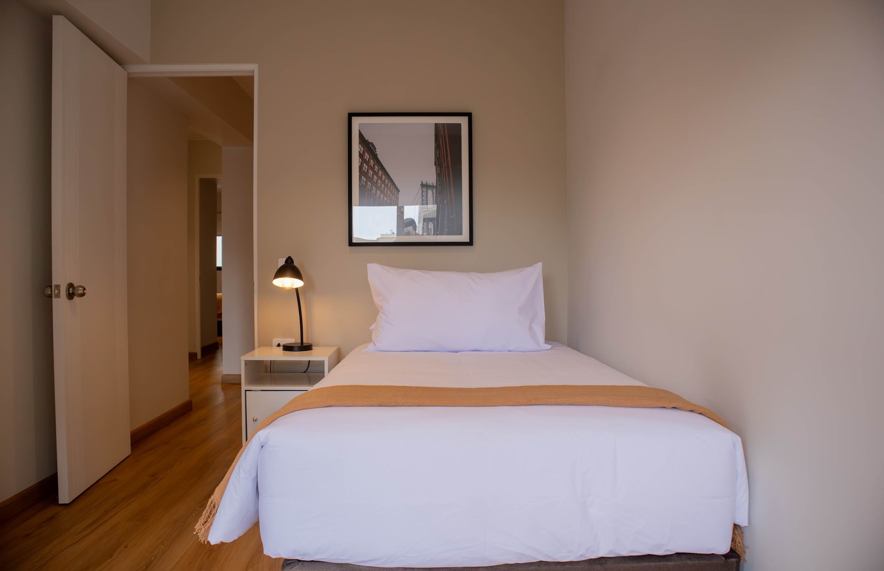 Une chambre d’hôtel avec un lit, une table de chevet, une lampe et un tableau encadré au mur.
