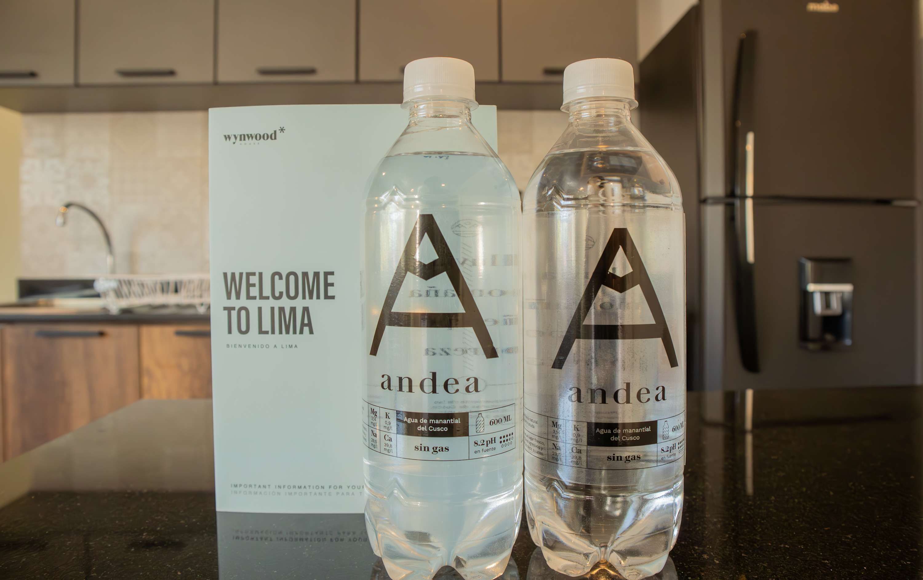 Dos botellas de agua con la marca 'andea' y un letrero que dice 'BIENVENIDOS A LIMA' al fondo.
