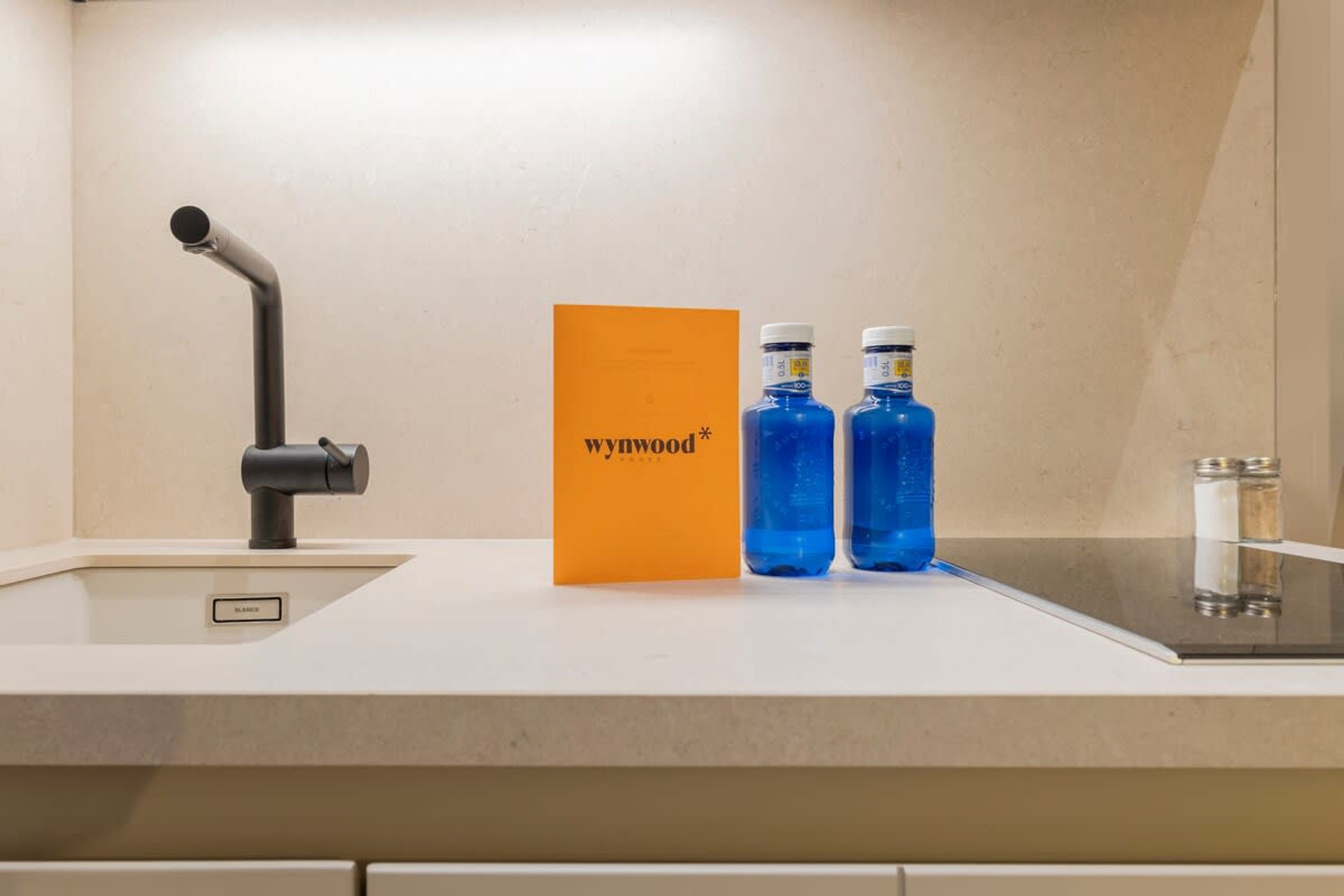 Un baño con un lavabo, un espejo y dos botellas azules en la encimera.