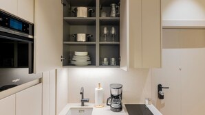 Una cuina moderna amb forn integrat, cafetera i un armari sobre l'aigüera.