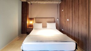 A bedroom with a bed, nightstand, lamp, and wooden panel walls. - w Bright & Stylish 2BR in Laureles (Medellín)