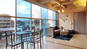 A modern interior with large windows, a dining area, a sofa, and a small table. - w Bright & Stylish 2BR in Laureles (Medellín)