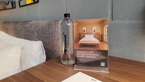 A hotel room with a wooden table, a bottle of water, a brochure, and a neatly folded white envelope. - w Stunning 1BR in Laureles (Medellín)