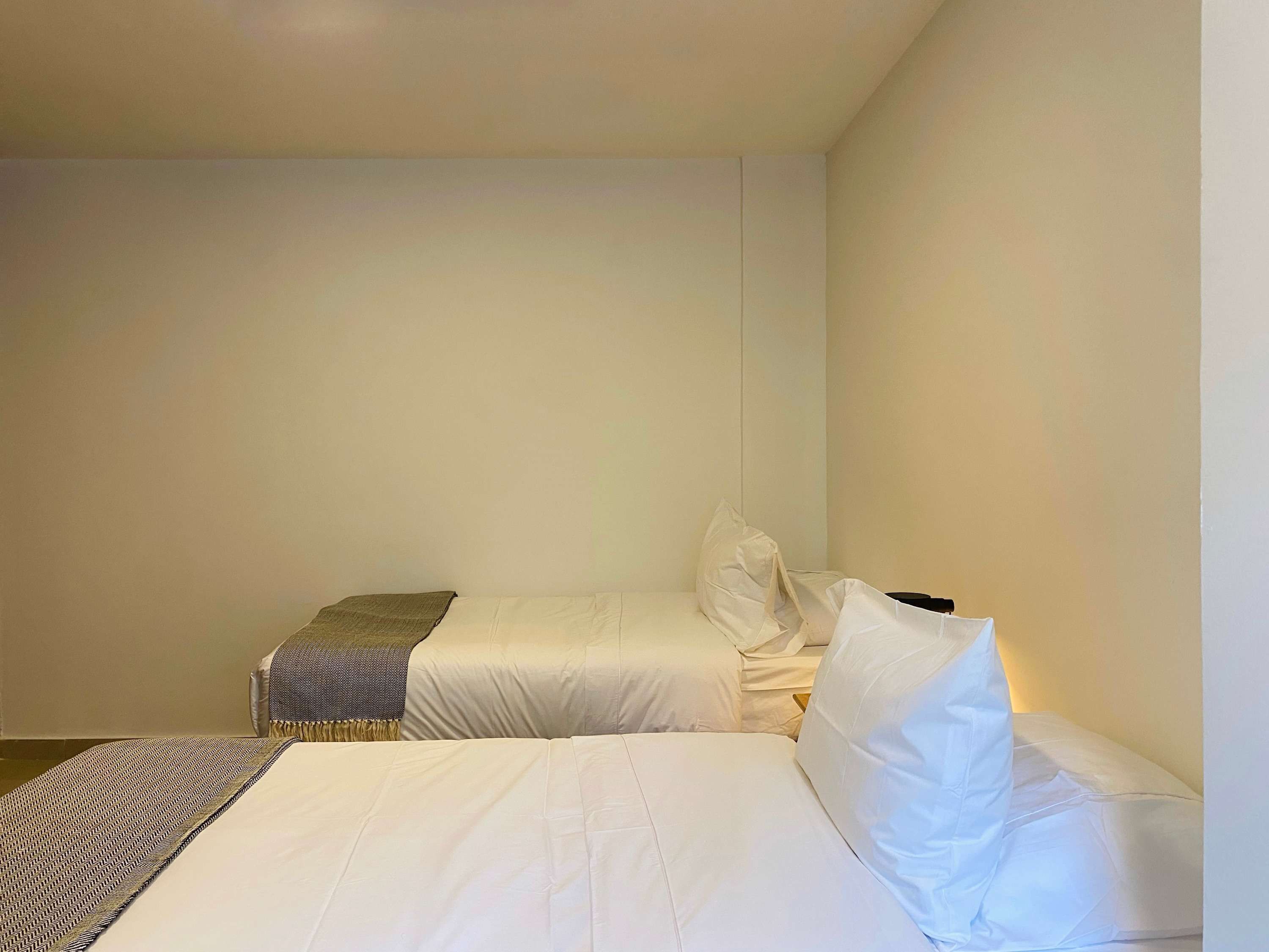 Una habitación sencilla y limpia con dos camas, una mesita y una silla.