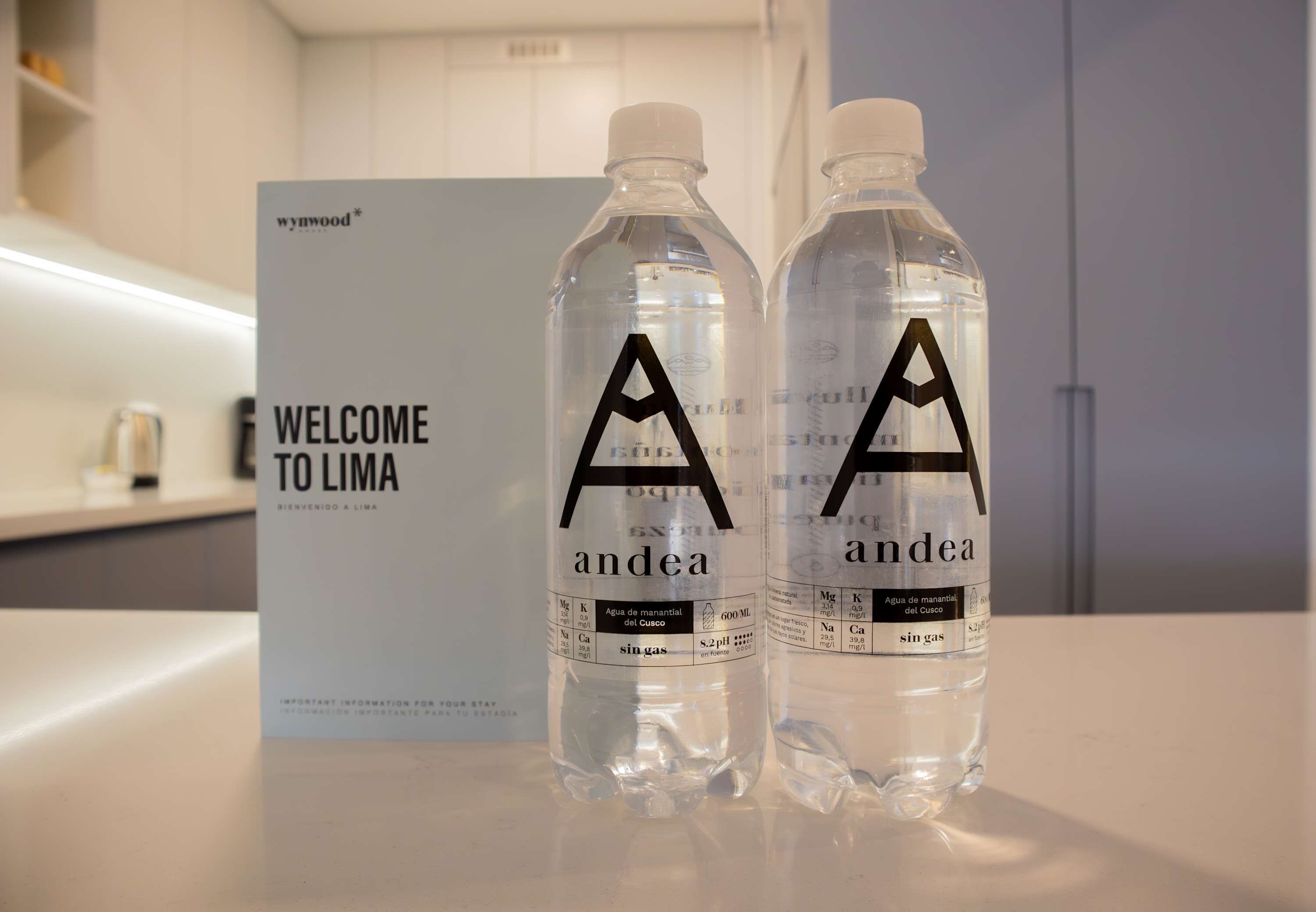 Two water bottles with 'andea' branding on a counter, with a 'WELCOME TO LIMA' sign in the background.