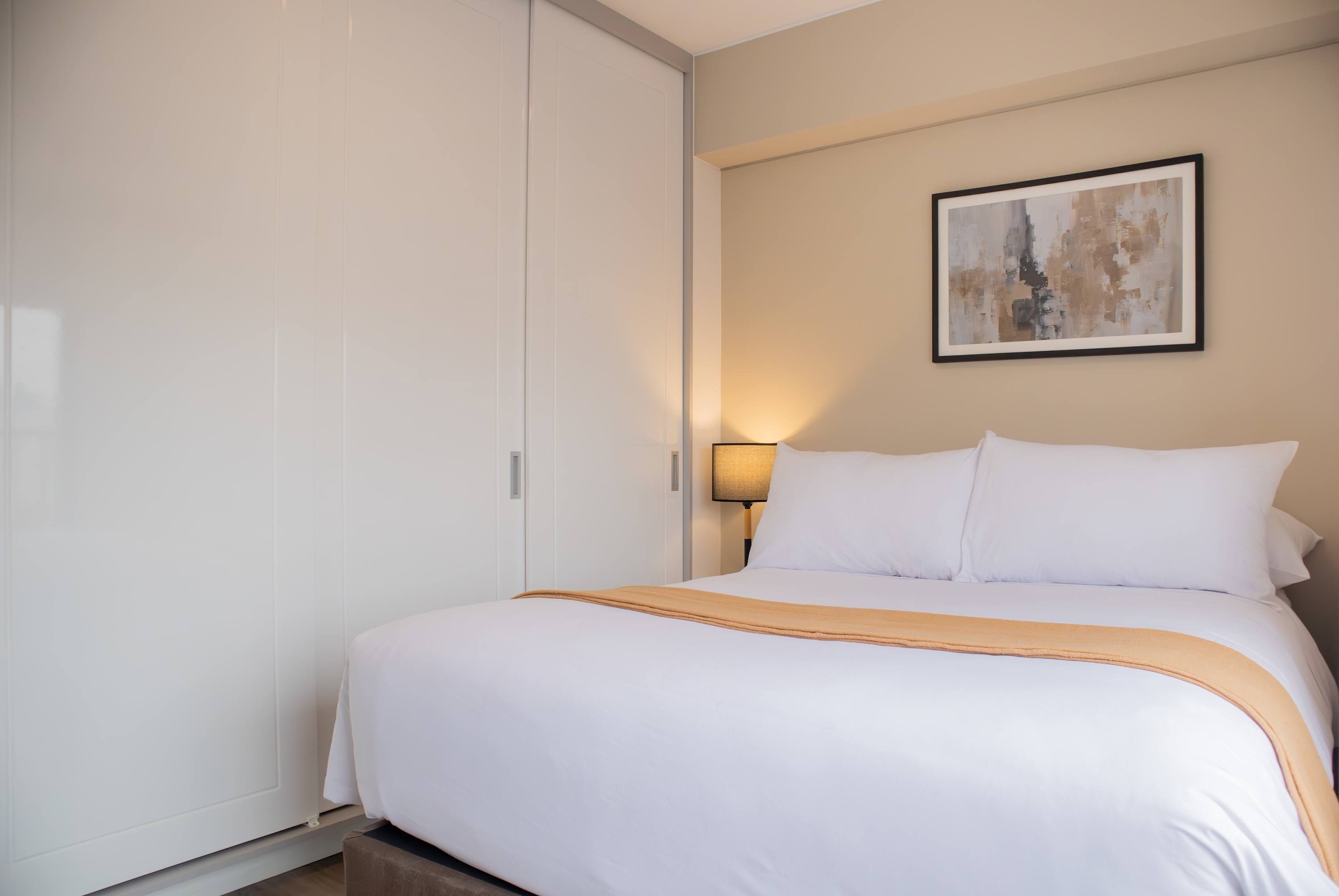 Ein Hotelzimmer mit einem großen Bett, einem Kleiderschrank und einer Wandlampe.