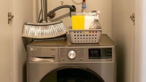 A compact laundry setup with a washing machine, a hose, and a mop. - w Gorgeous 1BR w Terrace in Miraflores (Lima)