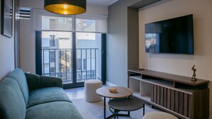 A modern living room with a sofa, a round table, and a TV mounted on the wall. - w Gorgeous 1BR w Terrace in Miraflores (Lima)