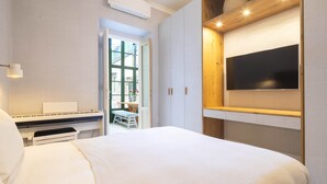 Una camera da letto con un letto, un pianoforte, una TV e una finestra con vista sull'esterno.