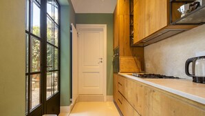 Una cucina stretta con mobili in legno, un piano di lavoro bianco e una finestra con vista sull'esterno.