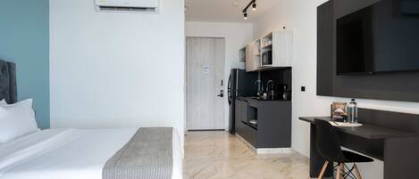 Una habitación de hotel moderna con una cama, un escritorio, un televisor y un rincón americano.