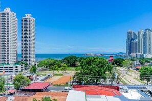 A cityscape with high-rise buildings, a clear blue sky, and a view of the ocean.