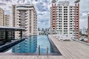 A rooftop pool with lounge chairs, surrounded by high-rise buildings.